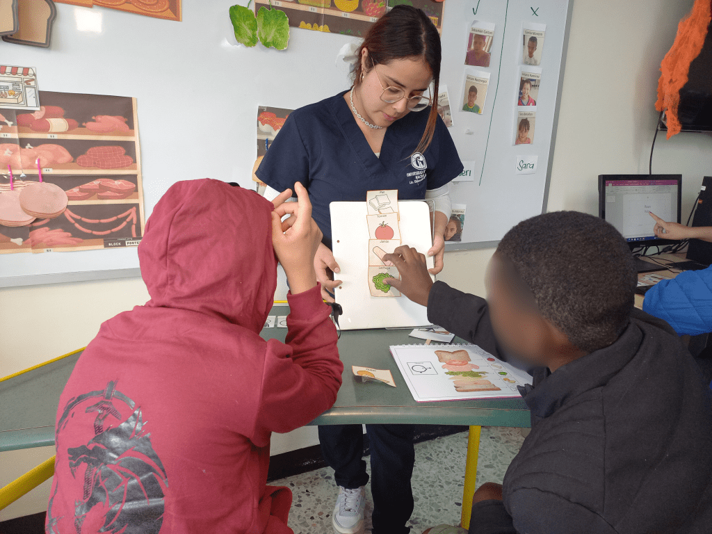 Estudiante en formación de la Licenciatura en Educación Especial durante la práctica de trabajo de grado con dos participantes del centro crecer.